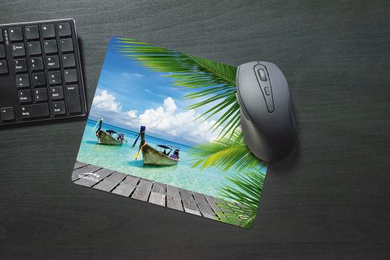 Ein Mousepad mit einem tropischen Strandmotiv zeigt Boote auf klarem Wasser, von Palmen umgeben, mit einer Computermaus und einer Tastatur im Hintergrund.