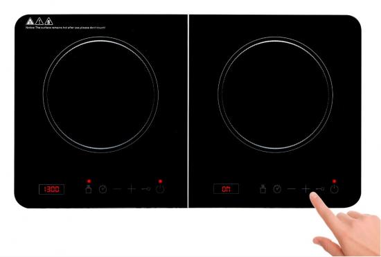Eine Hand bedient einen modernen Induktionsherd mit zwei Kochfeldern und Touch-Bedienfeld.