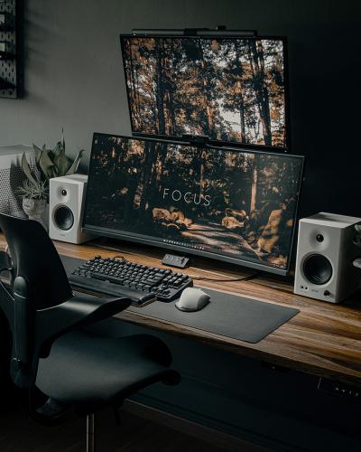 Ein elegant eingerichteter Arbeitsplatz mit zwei Monitoren, Tastatur, Maus, Lautsprechern und einem ergonomischen Stuhl