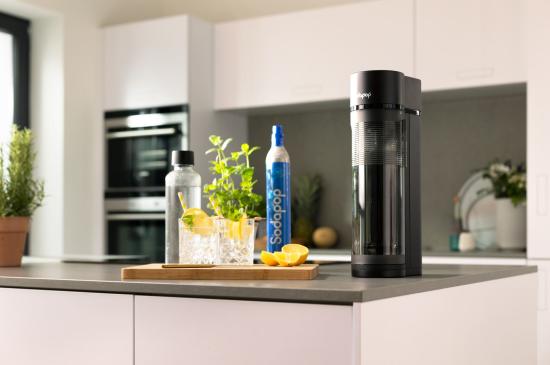 Ein moderner Wassersprudler und Zutaten für spritzige Getränke auf einer Küchenarbeitsplatte