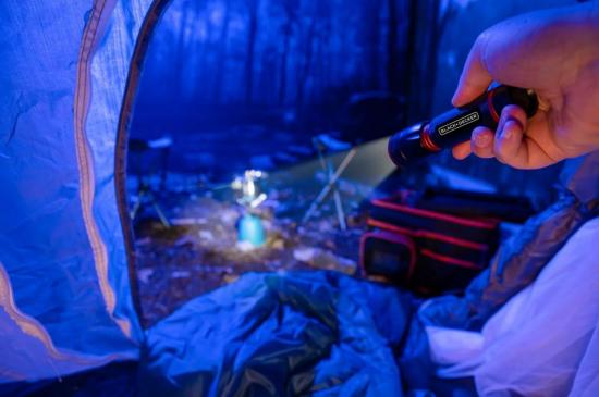 Zeltinnenansicht mit Taschenlampe, Schlafsack und Campingausrüstung im nächtlichen Wald