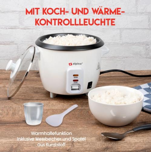 Reiskocher mit voller Schüssel Reis, Messbecher und Spatel auf Holztisch