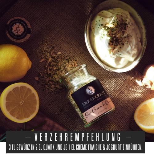 Ein Glas Ankerkraut Sour Cream & Onion Gewürz neben einer Schüssel Quark und frischen Zitronen, dekoriert mit Kräutern.