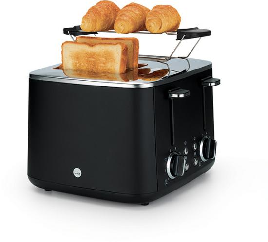 Toaster in Schwarz mit Brötchenaufsatz, auf dem Croissants liegen, daneben toastet eine Toastscheibe