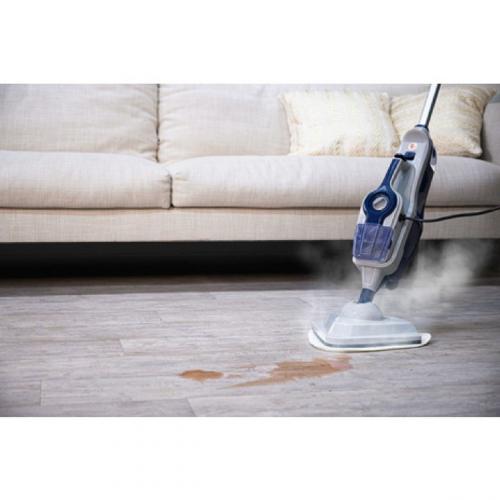 Ein Dampfreiniger reinigt einen Laminatboden vor einem Sofa und entfernt einen Fleck.